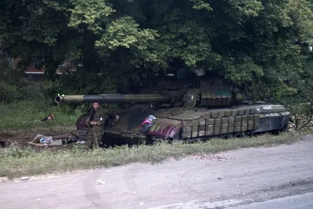 A pro-Russian rebel stands at a tank guarding a checkpoints in Shakhtarsk, Donetsk region, eastern Ukraine, Thursday, August 7, 2014. The possibility of an escalation in Ukraine as well as a ratcheting up in tensions between Western nations and Russia has cast a long shadow over the eurozone's fragile economic upswing. (Photo by Evgeniy Maloletka/AP Photo)