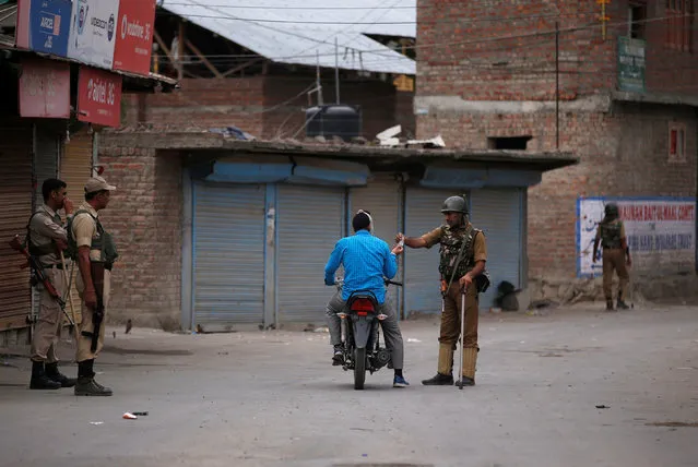 An Indian policeman checks the document of a motorcyclist during a curfew in Srinagar July 14, 2016. (Photo by Danish Ismail/Reuters)