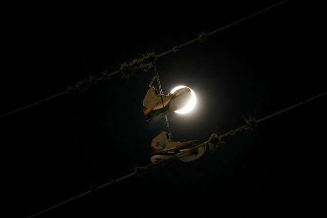Shoes hang on a power line as the full moon rises before the lunar eclipse in Caracas, Venezuela on September 17, 2024. (Photo by Leonardo Fernandez Viloria/Reuters)