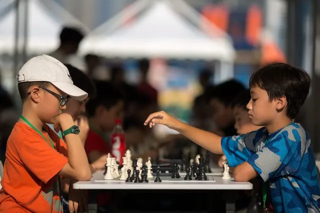 Two students play chess during an outdoor chess activity at the Central Harbourfront in Central, Hong Kong, China, 07 July 2016. The large-scale outdoor chess carnival features chess games, exhibitions and game booths. (Photo by Jerome Favre/EPA)