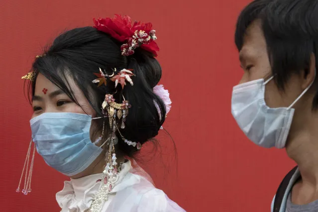 Residents wearing masks to help curb the spread the coronavirus walk along a retail street in Wuhan in central China's Hubei province, Thursday, April 9, 2020. Released from their apartments after a 2 1/2-month quarantine, residents of the city where the coronavirus pandemic began are cautiously returning to shopping and strolling in the street but say they still go out little and keep children home while they wait for schools to reopen. (Photo by Ng Han Guan/AP Photo)