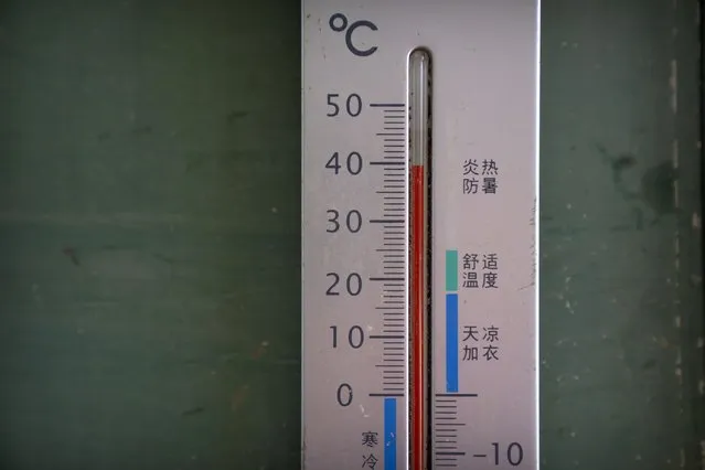 A thermometer shows a temperature of nearly 40 degrees Celsius (104 F) in the shade before midday in Longquan village in southwestern China's Chongqing Municipality, Saturday, August 20, 2022. (Photo by Mark Schiefelbein/AP Photo)
