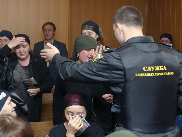 A bailiff tries to quieten the women during the trial at the court of Vladikavkaz Thursday 19 May 2005. Many people demand the lynching of Nurpasha Kulayev, the only suspected terrorist arrested during the Beslan hostage crisis. Three hundred and thirty people were killed in Beslan tragedy. (Photo by Zurab Kurtsikidze/EPA)