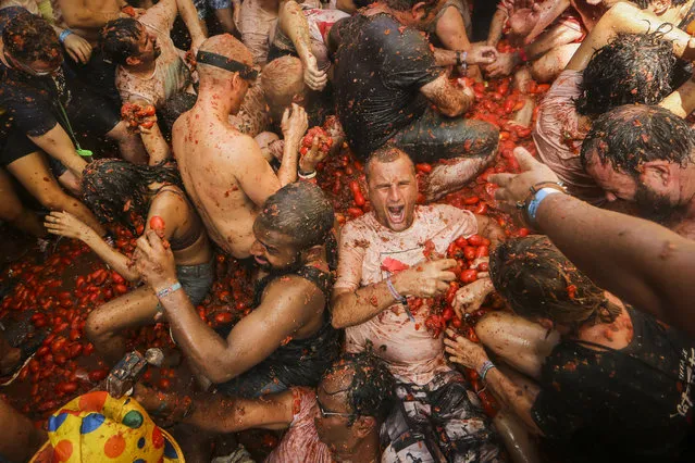 Revellers throw tomatoes at each other during the annual “Tomatina”, tomato fight fiesta in the village of Bunol near Valencia, Spain, Wednesday, August 31, 2022. The tomato fight took place once again following a two-year suspension owing to the coronavirus pandemic. (Photo by Alberto Saiz/AP Photo)