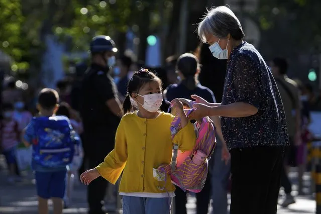 A woman wearing a face mask sends a child to a primary school in Beijing, Wednesday, September 7, 2022. (Photo by Andy Wong/AP Photo)