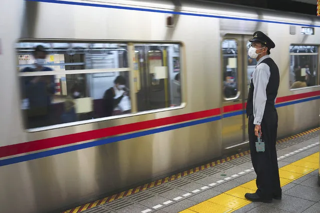 A station staff wearing face mask to prevent the spread of the new coronavirus looks at a subway arriving at a station in Tokyo Thursday, April 30, 2020. (Photo by Eugene Hoshiko/AP Photo)