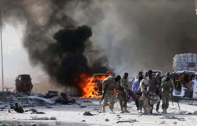 Somali Armed Forces evacuate their injured colleague, from the scene of an explosion in KM4 street in the Hodan district of Mogadishu on October 14, 2017. (Photo by Feisal Omar/Reuters)