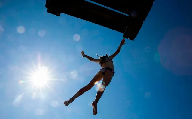 A girl is silhouetted against the sun as she jumps into the sea from a diving board on Lindoya island in Oslo on July 10, 2019. Forecasts predicts 27 celsius in the Norwegian capital on Wednesday and the water temprature is expected to reach 18. (Photo by Odd Andersen/AFP Photo)