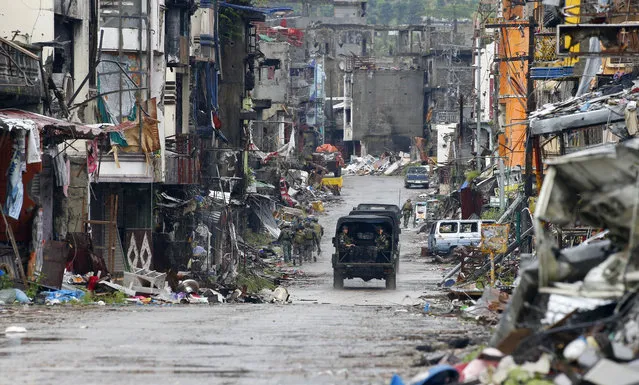 Amidst the ruins at “Ground Zero” Philippine troops return to their deployment after attending the ceremony wherein President Rodrigo Duterte declared the liberation of Marawi city in southern Philippines after almost five months of the siege by pro-Islamic State group militants Tuesday, October 17, 2017. Gunfire rang out sporadically and explosions thudded as Philippine soldiers fought Tuesday to gain control of the last pocket of Marawi controlled by Islamic militants as President Duterte declared the southern city liberated from “terrorist influence”. (Photo by Bullit Marquez/AP Photo)