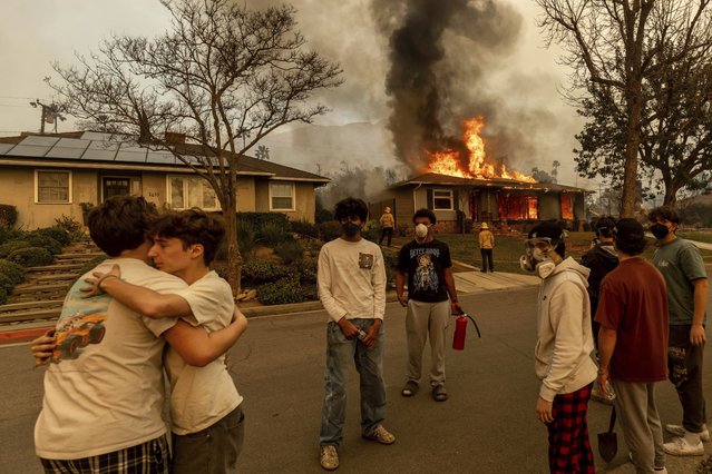 Residents embrace outside of a burning property as the Eaton Fire swept through Wednesday, January 8, 2025 in Altadena, Calif. (Photo by Ethan Swope/AP Photo)