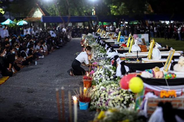 A person pays tribute at the caskets of victims, on the day of a cremation at Wat Rat Samakee temple, following a mass shooting at a day care centre, in the town of Uthai Sawan, in the province of Nong Bua Lam Phu, Thailand on October 11, 2022. (Photo by Athit Perawongmetha/Reuters)