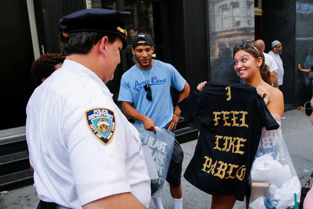 A shopper shows her “The Life of Pablo” merchandise to NYPD officers after visiting a pop up store featuring fashion by Kanye West in Manhattan, New York, U.S., August 19, 2016. (Photo by Eduardo Munoz/Reuters)