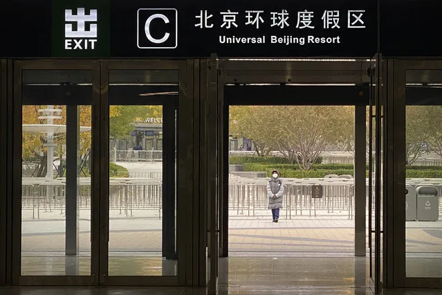 A worker wearing a face mask stands outside an exit from a subway station to stop visitors from going to the Universal Studios Beijing resort, which according to a notice was closed for epidemic control, in Beijing, Wednesday, October 26, 2022. The Chinese city of Shanghai started administering an inhalable COVID-19 vaccine on Wednesday in what appears to be a world first. (Photo by Mark Schiefelbein/AP Photo)