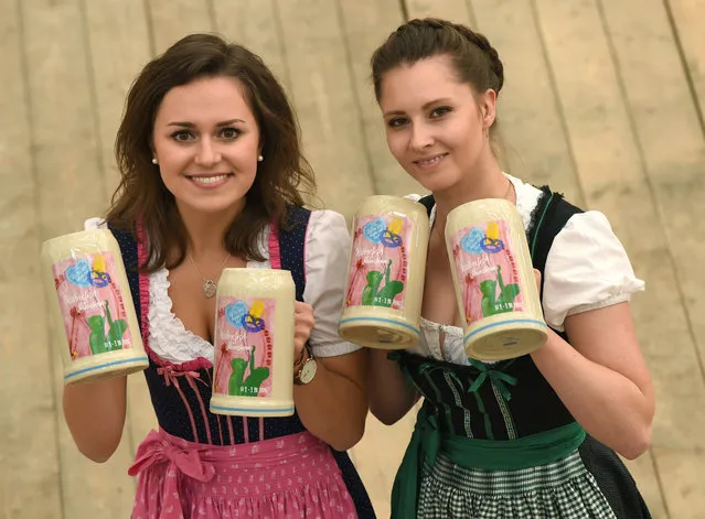 Women wearing the traditional Bavarian Dirndl presents the new Oktoberfest beer mug during a press conference at the Oktoberfest grounds in Munich, southern Germany, on August 23, 2016. The world largest beer festival Oktoberfest will run from September 17 until October 3, 2016. (Photo by Christof Stache/AFP Photo)