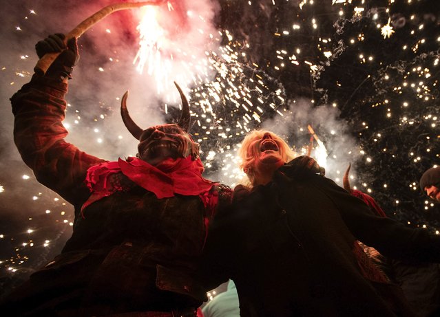 A participant dressed up as a demon brandishes a stick with fireworks during the traditional Correfoc (fire-run) festival in Palma de Mallorca on January 28, 2024. The Correfoc is a night of revelry in which participants dress up as demons and devils, and run through the streets scaring people with fire and fireworks. (Photo by Jaime Reina/AFP Photo)