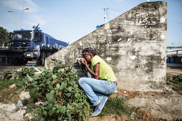 A Gabonese woman takes cover protecting her mouth from the tear gas as supporters of opposition leader Jean Ping protest, trying to reach the electoral commission, in Libreville on August 31, 2016. Bongo won by a narrow 5,594 votes of a total 627,805 registered voters. Turnout was 59.46 percent nationwide but soared to 99.93 percent in one of the country's nine provinces – the Haut-Ogooue, heartland of Bongo's Teke ethnic group – in a result hotly contested by the opposition. (Photo by Marco Longari/AFP Photo)