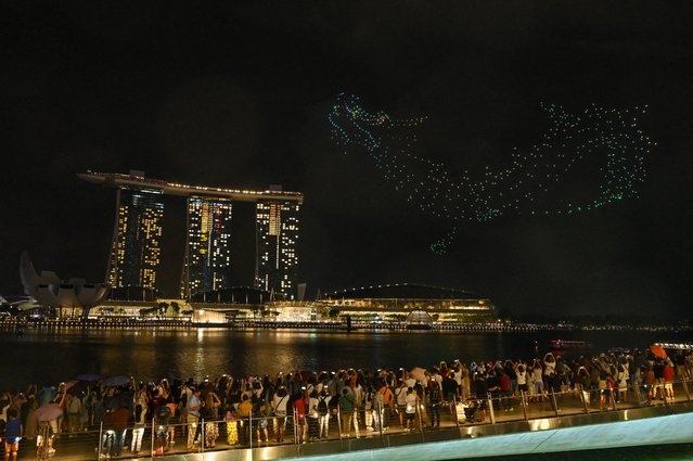 People watch some 1,500 drones forming a dragon during a performance titled 'The Legend Of The Dragon Gate' above the Marina bay waterfront on the first day of the Lunar New Year in Singapore on February 10, 2024. (Photo by Roslan Rahman/AFP Photo)