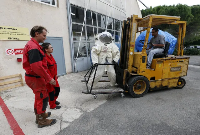 Comex Space division manager Peter Weiss (L) and Comex project engineer Virginie Taillebot (2ndL) move the Gandolfi space suit before a training session in Marseille October 21, 2014. (Photo by Jean-Paul Pelissier/Reuters)