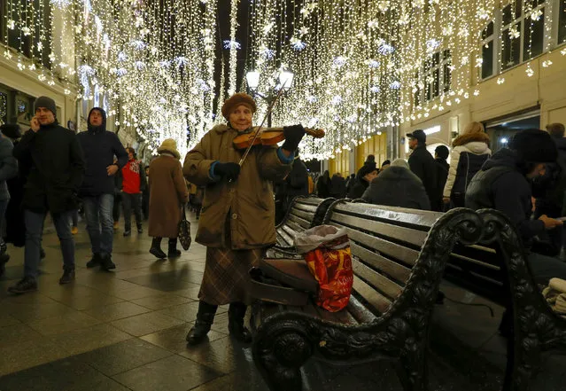 A woman plays a violin on the street, decorated with festive lights prior to the New Year and Christmas holidays, in central Moscow, Russia December 23, 2017. (Photo by Grigory Dukor/Reuters)