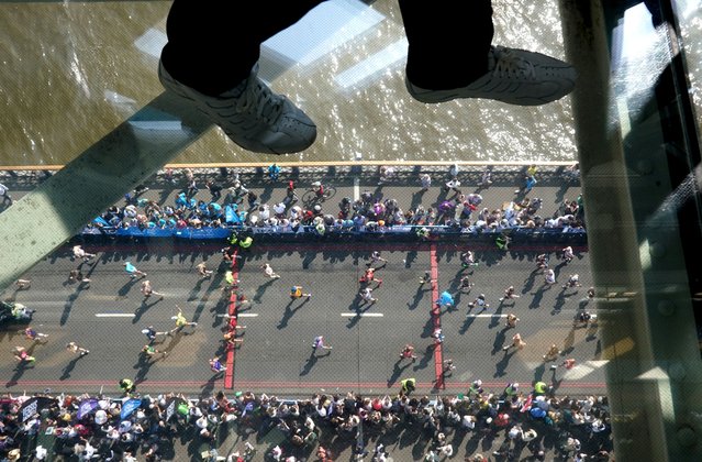 Visitors to Tower Bridge walk across the walkway as runners in the mass participation race go by during the TCS London Marathon on Sunday, April 27, 2025. (Photo by Jonathan Brady/PA Images via Getty Images)