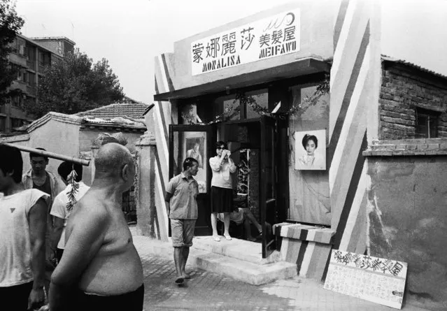 Locals walk past a barbershop in the Sanlitun area of Beijing in 1982. (Photo by Reuters/China Daily)
