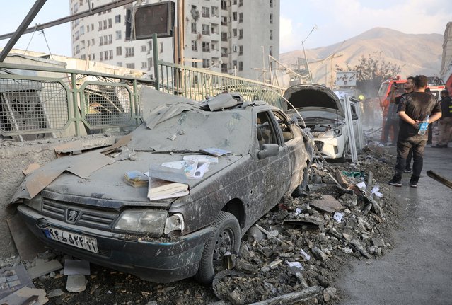 People gather near damaged vehicles in the aftermath of Israeli strikes, in Tehran, Iran, on June 13, 2025. (Photo by Majid Asgaripour/WANA (West Asia News Agency) via Reuters)