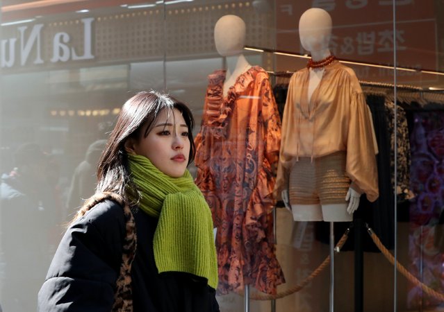 On the morning of the February 18th, 2025, a foreign tourist wearing a scarf walks past a store window with spring clothes hanging on the street in Myeongdong, Seoul. (Photo by Park Seong-won)