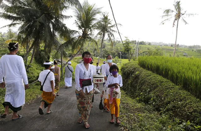 People wearing face masks as a precaution against coronavirus outbreak walk to a temple at a village in Bali, Indonesia Monday, September 21, 2020. (Photo by Firdia Lisnawati/AP Photo)
