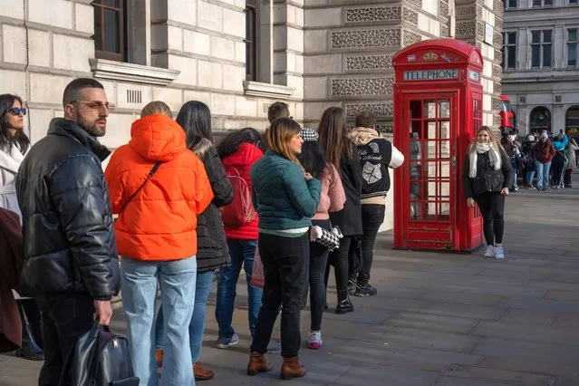 A woman has her photograph taken next to an old-fashioned British telephone box as others queue to take the same picture on January 30, 2023 in London, England. More than 5,000 red boxes have been adopted for new uses including as food banks, libraries and defibrillator stations. (Photo by Carl Court/Getty Images)