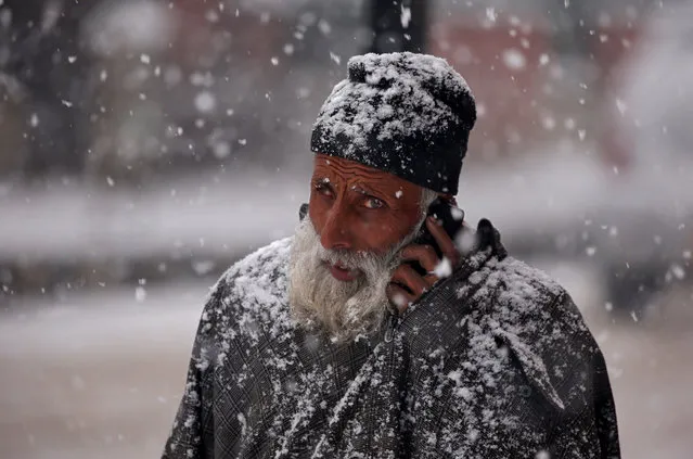 A man speaks on his mobile phone as he walks during a snowfall in Srinagar February 12, 2018. (Photo by Danish Ismail/Reuters)