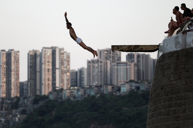 A person jumps off from a diving board into the Jialing River amid a red alert for heat in Chongqing, China on July 31, 2025. (Photo by Go Nakamura/Reuters)