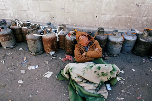 A man sleeps next to a queue of cooking gas cylinders outside a gas filling station amid a scarcity in cooking gas supplies in Sanaa, Yemen March 4, 2018. (Photo by Khaled Abdullah/Reuters)