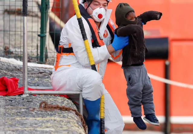 Rescuers help a migrant child disembark from a Spanish coast guard vessel in the port of Arguineguin, in the island of Gran Canaria, Spain on February 8, 2023. (Photo by Borja Suarez/Reuters)