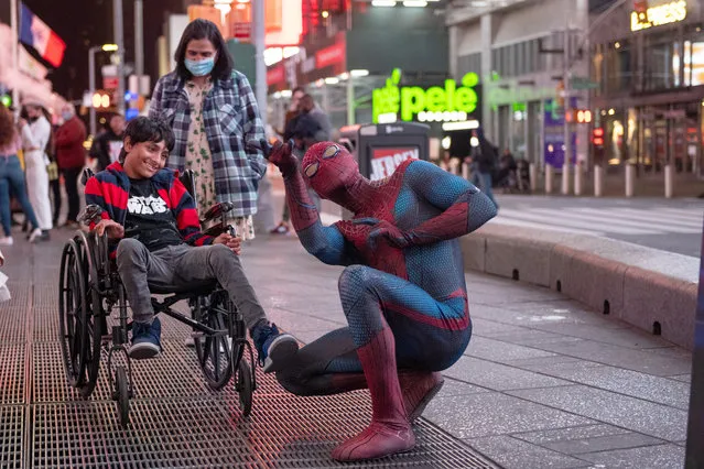 Junaid watches as Andreas Alfaro, dressed in a Spider- Man costume, makes the Spider-Man web shooting hand gesture in Times Square during the Coronavirus pandemic on October 19, 2020 in New York City. (Photo by Alexi Rosenfeld/Getty Images)