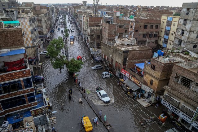 Commuters make their way through a flooded street during heavy monsoon rains in Hyderabad, in Sindh province, on July 14, 2025. Monsoon rains in Pakistan have been linked to more than 110 deaths including dozens of children since they arrived in late June, according to government figures released on July 14. (Photo by Husnain Ali/AFP Photo)