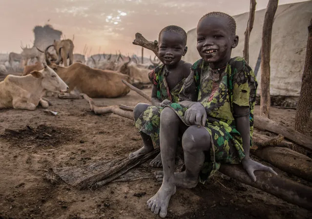 Sudanese boys from Dinka tribe pose in the early morning at their cattle camp in Mingkaman, Lakes State, South Sudan on March 4, 2018. (Photo by  Stefanie Glinski/AFP Photo)