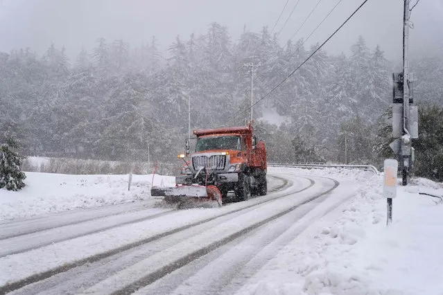A plow clears snow on Mount Baldy Road in the town of Mount Baldy, California, on February 24, 2023. Californians more used to flip flops and shorts were wrapping up warm Thursday as a rare winter blizzard, the first in more than 30 years, loomed over Los Angeles, even as the US East Coast basked in summer-like temperatures. (Photo by Allison Dinner/AFP Photo)