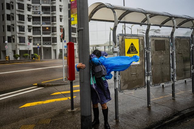 A woman holds onto a lamppost to avoid being blown away by strong winds at a bus stop in Heng Fa Chuen as Super Typhoon Ragasa hits Hong Kong on September 24, 2025. Hong Kong's weather service issued the highest level of typhoon warning in the early hours, as Super Typhoon Ragasa brought powerful winds and lashing rain to the southern Chinese coast. (Photo by Leung Man Hei/AFP Photo)