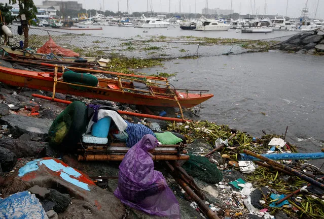 A fisherman stays near his boat docked along the shore overlooking yachts in Manila bay after Typhoon Sarika slammed central and northern Philippines, October 16, 2016. (Photo by Erik De Castro/Reuters)