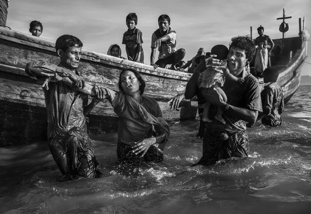 Rohingya Refugees Flee Into Bangladesh:  A Rohingya refugee is helped from a boat as she arrives at Shah Porir Dwip, near Cox’s Bazar, Bangladesh, October 1, 2017. Attacks on the villages of Rohingya Muslims in Myanmar, and the burning of their homes, led to hundreds of thousands of refugees fleeing into Bangladesh on foot or by boat. Many died in the attempt. According to UNICEF, more than half of those fleeing were children. In Bangladesh, refugees were housed in existing camps and makeshift settlements. Conditions became critical; basic services came under severe pressure and, according to a Médecins Sans Frontières physician based there, most people lacked clean water, shelter and sanitation, bringing the threat of disease. (Photo by Kevin Frayer/Getty Images//World Press Photo)
