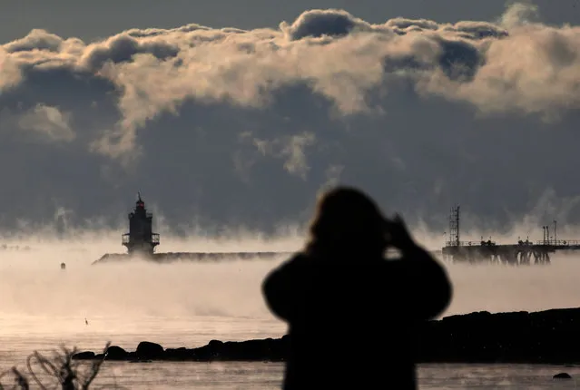 A woman photographs the sea smoke rising from the harbor in Portland, Maine, where the temperature at dawn was minus 9 degrees F, Thursday, January 8, 2015. Dangerously cold air has sent temperatures plummeting around the U.S. (Photo by Robert F. Bukaty/AP Photo)