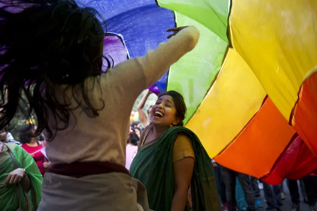 Participants dance under a rainbow flag during a gay pride parade in New Delhi, India, Sunday, November 29, 2015. Hundreds of gay rights activists danced to drum beats and held colorful balloons as they marched celebrating what they call the diversity of gender and sexuality. (Photo by Tsering Topgyal/AP Photo )