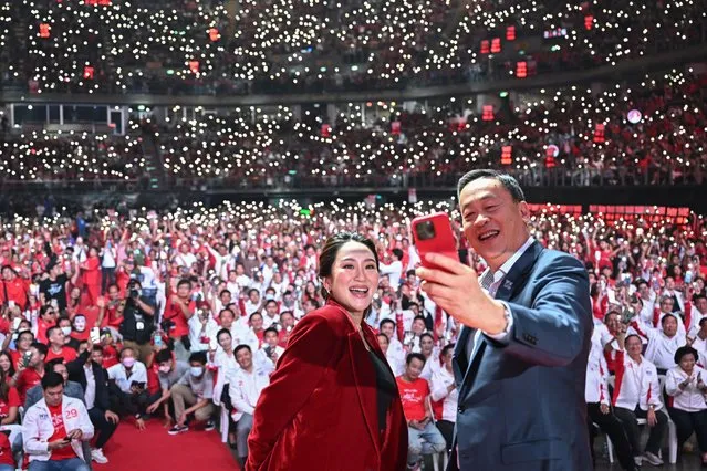 Pheu Thai Party's prime ministerial candidates Paetongtarn Shinawatra (L) and Srettha Thavisin (R) take a selfie photo on stage at the party's final campaign event in Bangkok on May 12, 2023, ahead of Thailand's May 14 general election. (Photo by Manan Vatsyayana/AFP Photo)