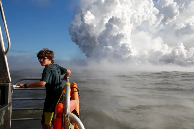 Ira Mullins, 13, of Mountain View, watches as lava flows into the Pacific Ocean in the Kapoho area, east of Pahoa, during ongoing eruptions of the Kilauea Volcano in Hawaii, U.S., June 4, 2018. (Photo by Terray Sylvester/Reuters)