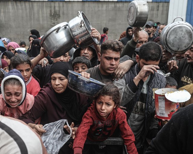 Displaced Palestinians receive meals distributed by a charity organization in the Nuseirat camp as the food crisis continues due to restrictions on the entry of humanitarian aid in Deir al-Balah, Gaza, on December 13, 2025. (Photo by Moiz Salhi/Anadolu via Getty Images)