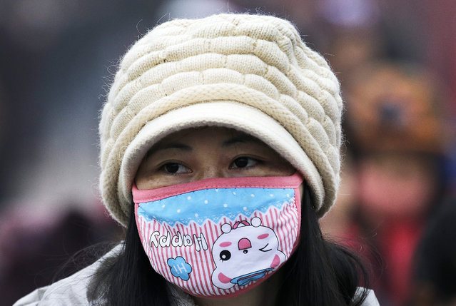  In this December 8, 2015 photo, a woman wears a mask to protect herself from pollutants near the Forbidden City on a heavily polluted day in Beijing. (Photo by Andy Wong/AP Photo)