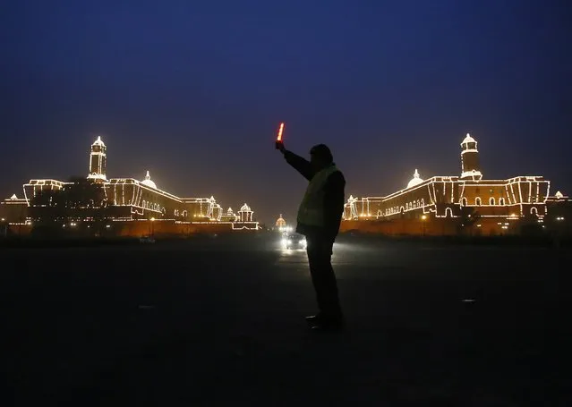 A traffic policeman signals traffic to stop near the Indian Defence Ministry (L) and Home Ministry buildings, which are lit up ahead of the country's Republic Day celebrations in New Delhi January 20, 2015. (Photo by Anindito Mukherjee/Reuters)