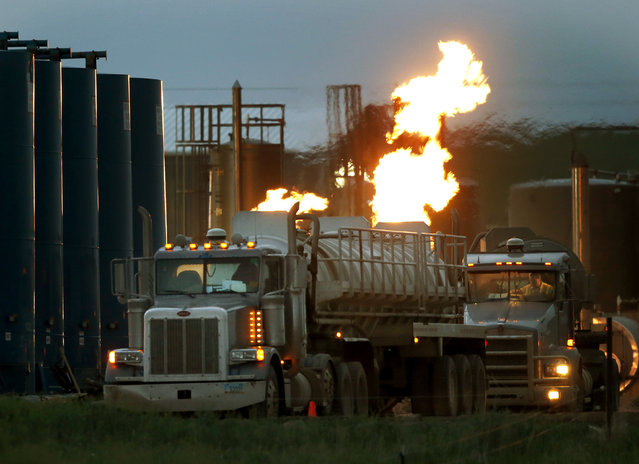 In this June 9, 2014 file photo, drivers and their tanker trucks, capable of hauling water and hydraulic fracturing liquid, line up near a natural gas burn off flame and storage tanks in Williston, N.D. According to a 2005-12 study at Geisinger Clinic in Pennsylvania, fracking may worsen asthma in children and adults who live near natural gas drilling sites. People with asthma are vulnerable to air pollution, and diesel exhaust from heavy truck traffic involved in the process may be one of the culprits, although the study doesn't prove what caused patients' symptoms. (Photo by Charles Rex Arbogast/AP Photo)