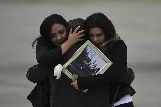 Relatives of the slain members of the news team from Ecuadorean newspaper El Comercio, embrace as the coffins containing the remains of their loved ones are carried onto an airplane of the Ecuadorean Air Force to be flown to Quito, at the Alfonso Bonilla Aragon airport in Palmira, Colombia, on June 27, 2018. The trio -journalist Javier Ortega, photographer Paul Rivas and driver Efrain Segarra- had been kidnapped and slain while covering a story on violence along the remote border with Colombia prompting both countries to send troops to hunt down the perpetrators. (Photo by Luis Robayo/AFP Photo)