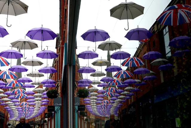 A man walks under a display of umbrellas in Durham, Britain on May 5, 2023. (Photo by Lee Smith/Reuters)